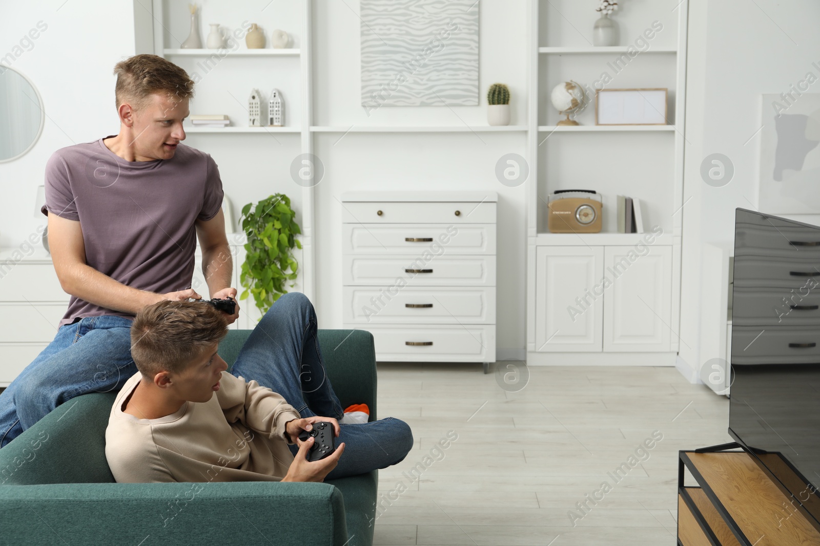 Photo of Young brothers playing video game on sofa at home