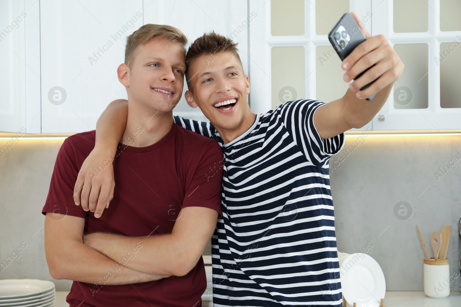 Photo of Two happy brothers taking selfie in kitchen