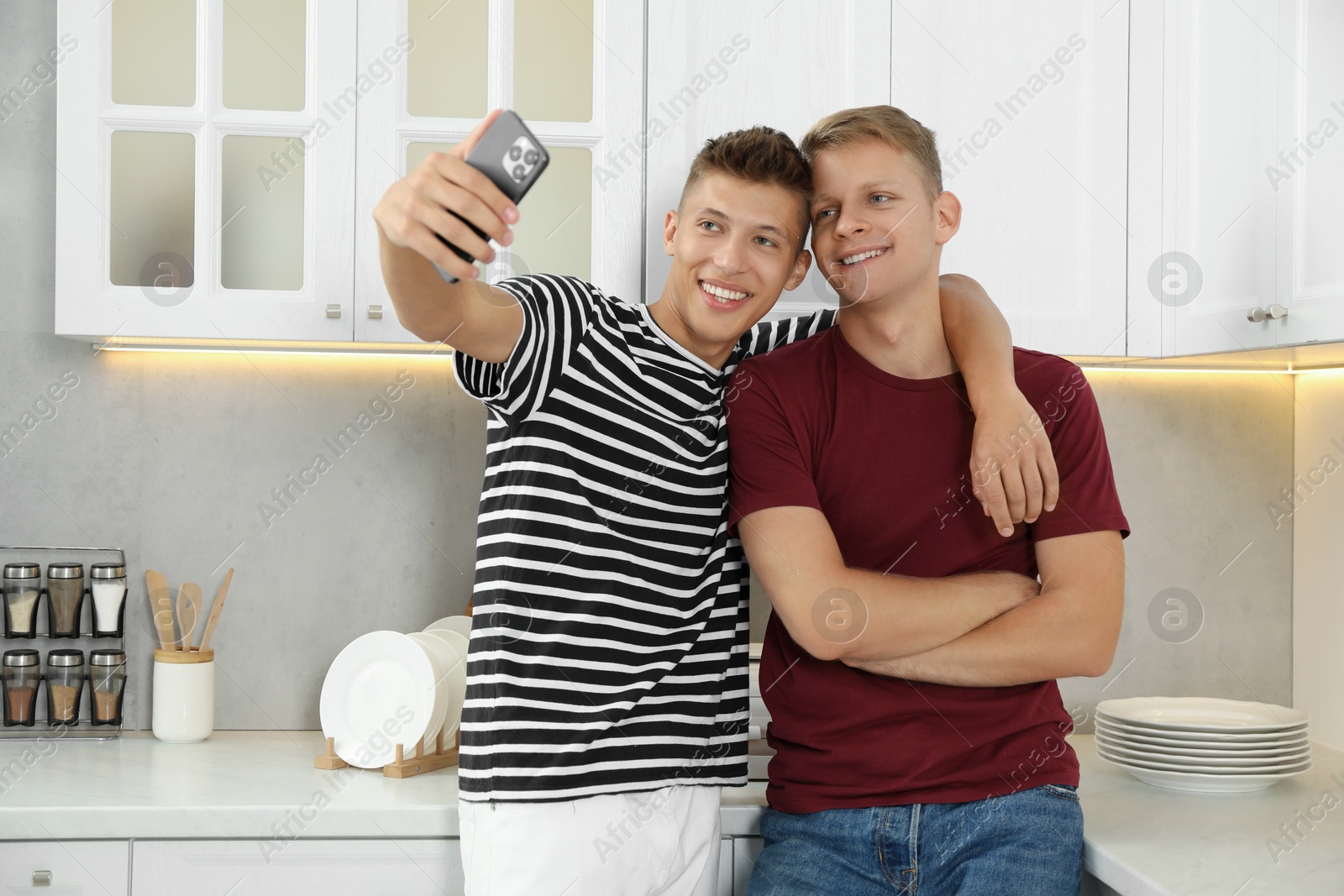 Photo of Two happy brothers taking selfie in kitchen