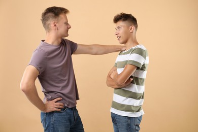 Photo of Two young brothers talking on beige background