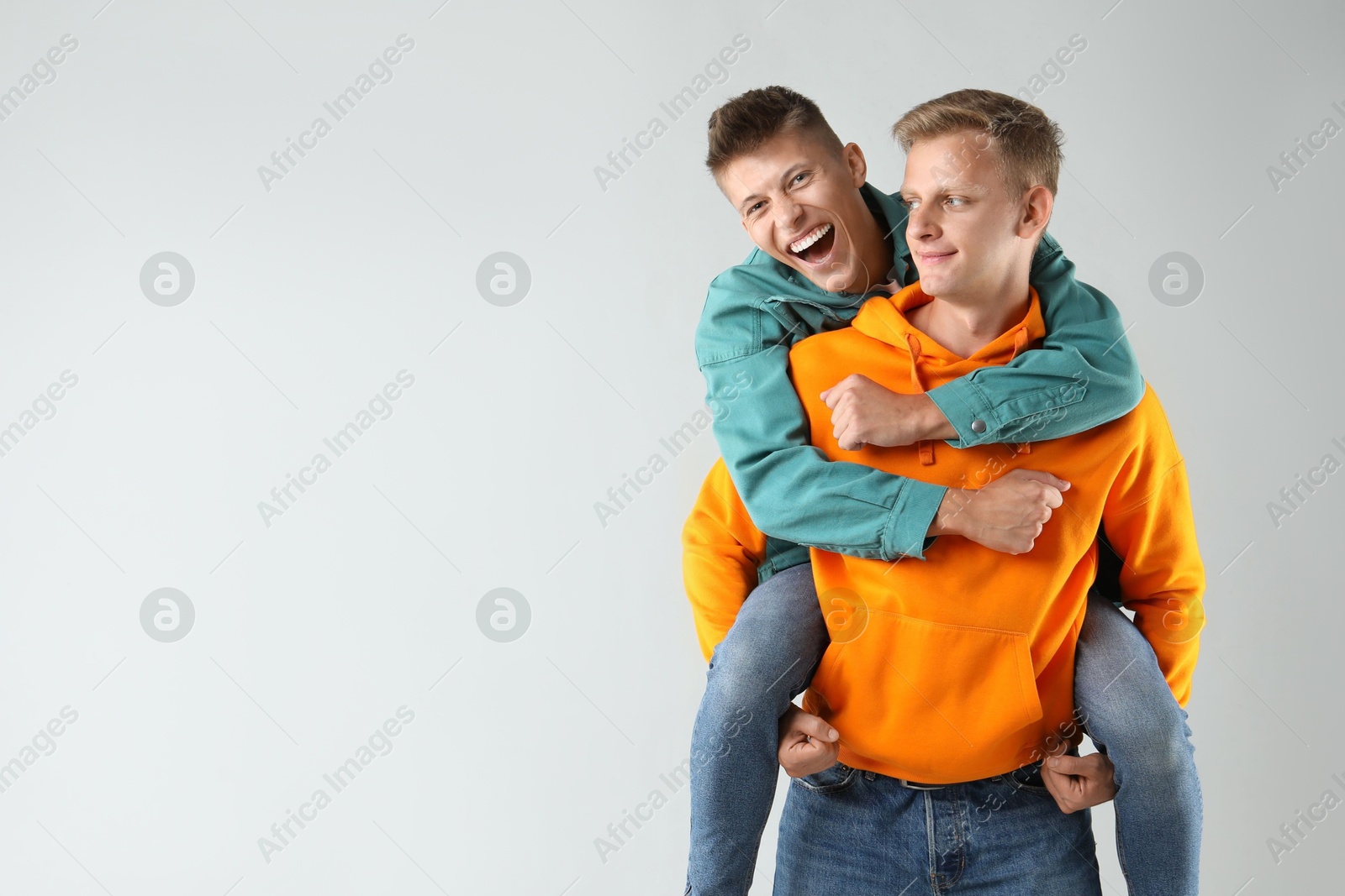 Photo of Two happy brothers having fun on light background. Space for text