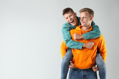 Two happy brothers having fun on light background. Space for text