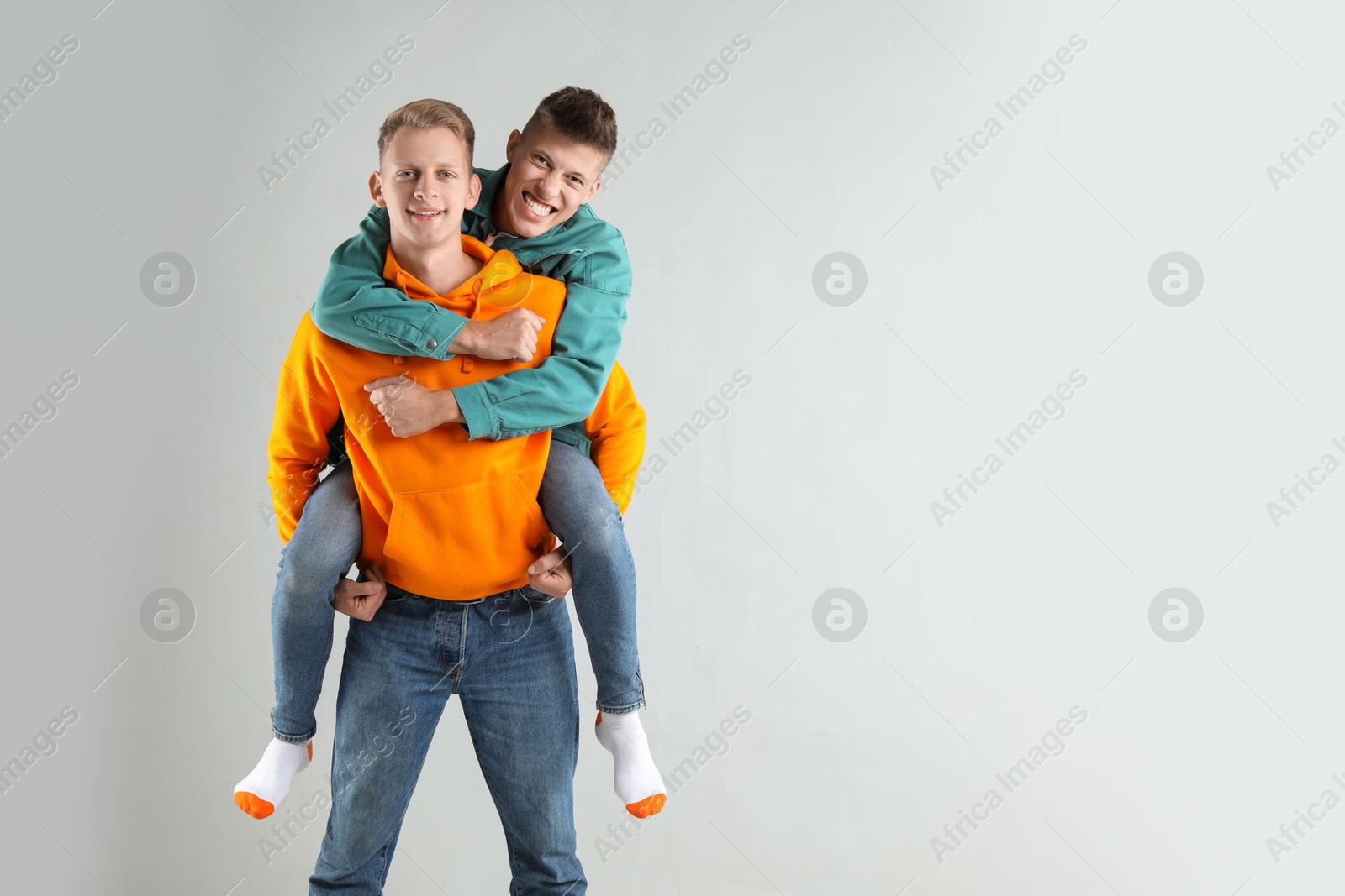 Photo of Two happy brothers having fun on light background. Space for text