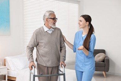 Nurse helping senior man with walking frame in clinic