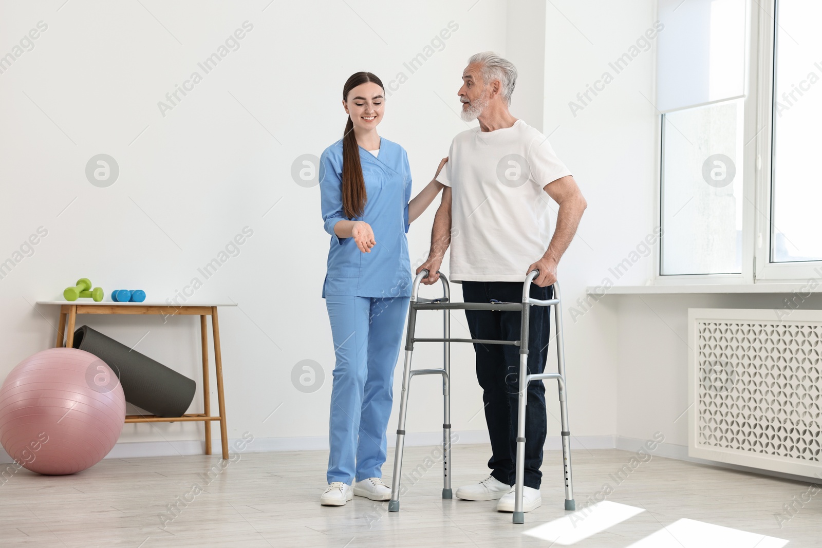 Photo of Nurse helping senior man with walking frame in clinic