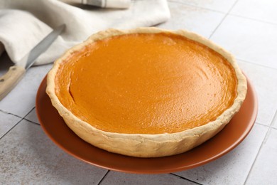 Photo of Tasty homemade pumpkin pie on light tiled table, closeup