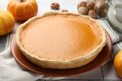 Tasty homemade pumpkin pie and ingredients on table, closeup