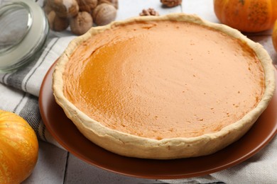 Photo of Tasty homemade pumpkin pie and ingredients on table, closeup