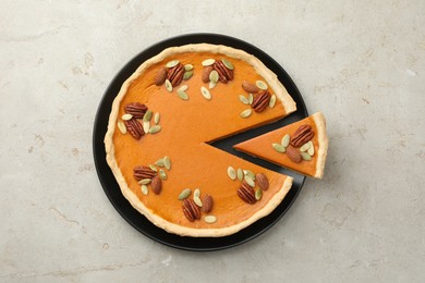 Tasty homemade pumpkin pie with seeds and nuts on grey table, top view