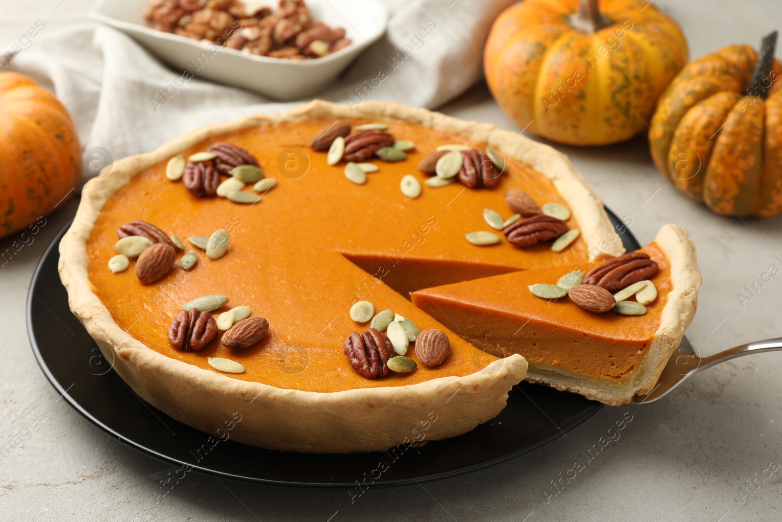 Photo of Taking piece of tasty homemade pumpkin pie at grey table, closeup