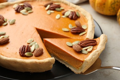 Photo of Taking piece of tasty homemade pumpkin pie at grey table, closeup