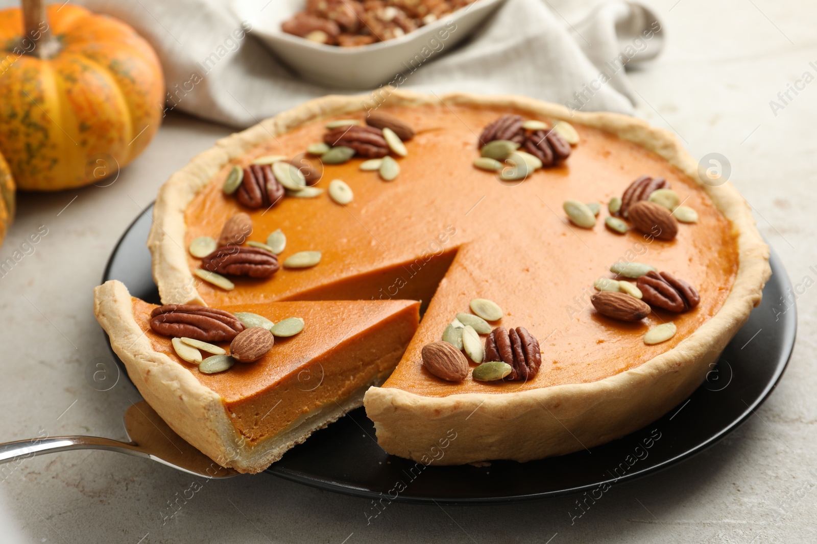 Photo of Taking piece of tasty homemade pumpkin pie at grey table, closeup