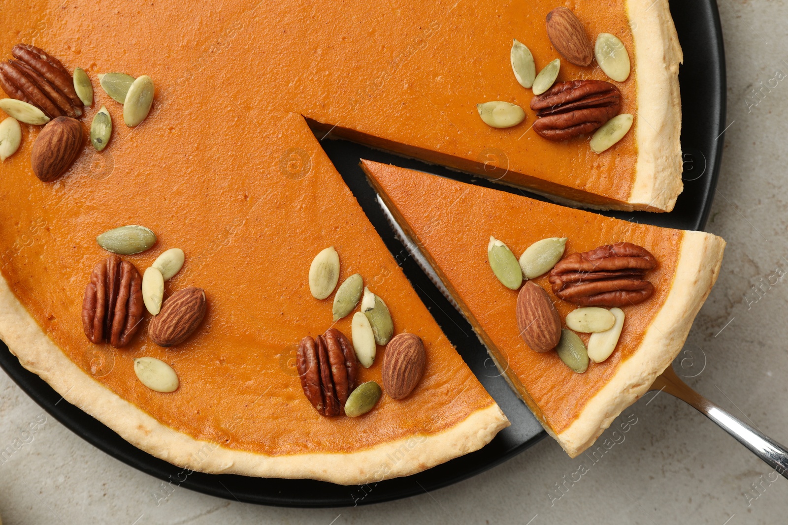 Photo of Taking piece of tasty homemade pumpkin pie at grey table, top view