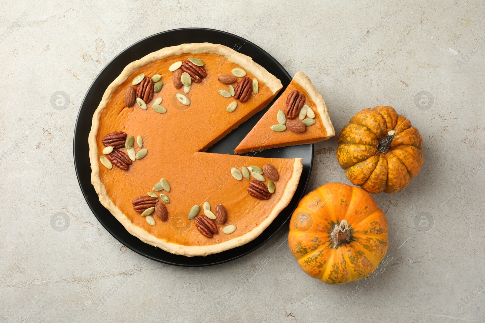 Photo of Tasty homemade pumpkin pie and fresh pumpkins on grey table, top view