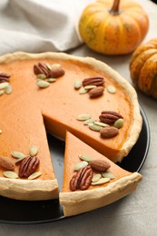 Tasty homemade pumpkin pie and fresh pumpkins on grey table, closeup