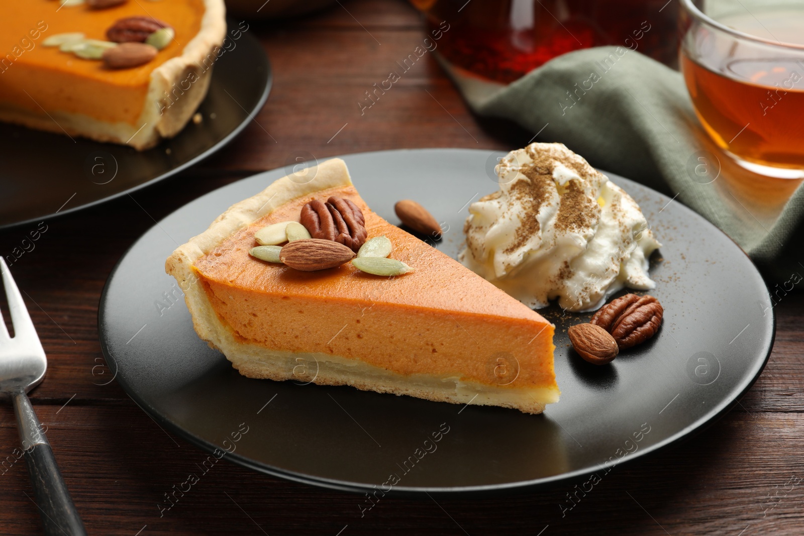 Photo of Piece of tasty homemade pumpkin pie served on wooden table, closeup