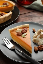 Photo of Piece of tasty homemade pumpkin pie served on wooden table, closeup