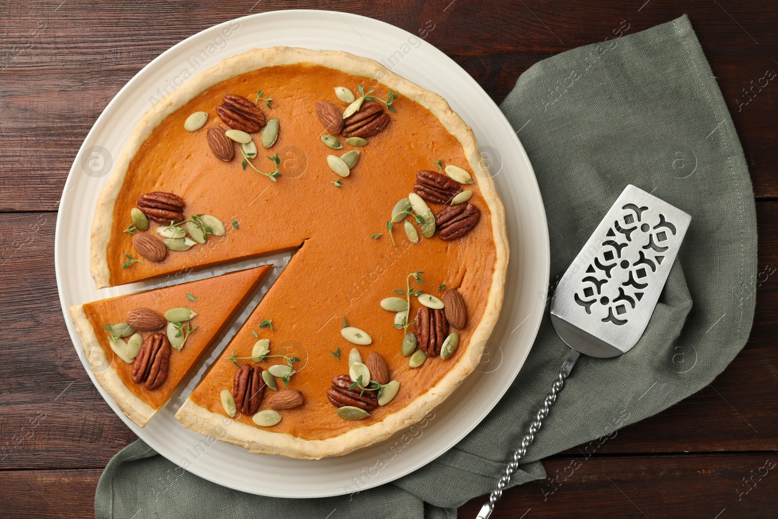 Photo of Tasty homemade pumpkin pie and server on wooden table, top view