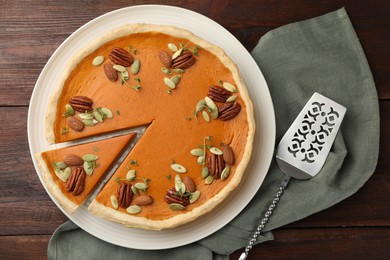 Photo of Tasty homemade pumpkin pie and server on wooden table, top view