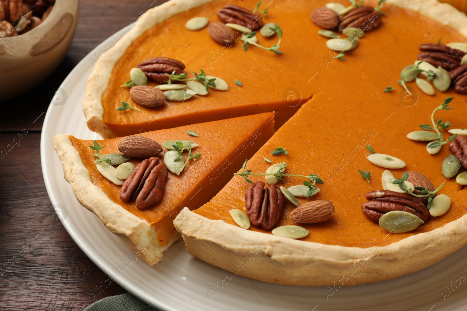 Photo of Tasty homemade pumpkin pie with nuts and seeds on table, closeup