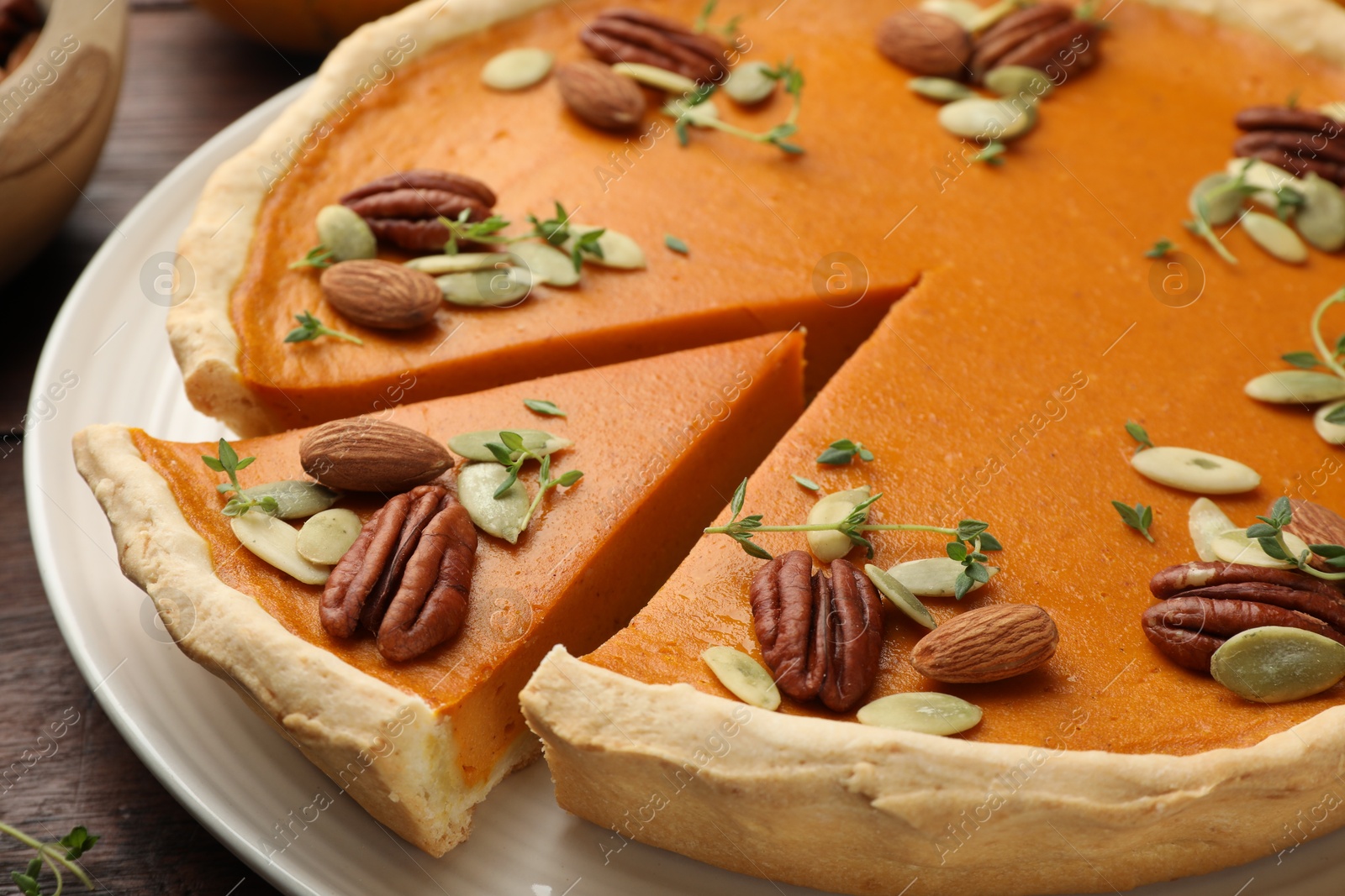 Photo of Tasty homemade pumpkin pie with nuts and seeds on table, closeup