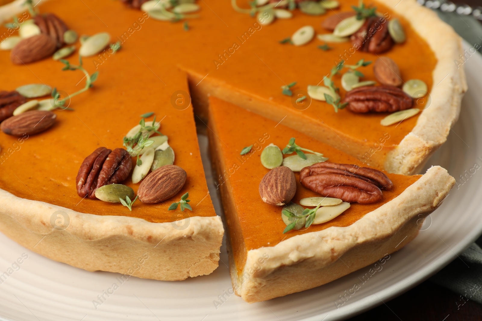 Photo of Tasty homemade pumpkin pie with nuts and seeds on table, closeup