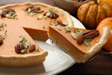 Taking piece of tasty homemade pumpkin pie at wooden table, closeup