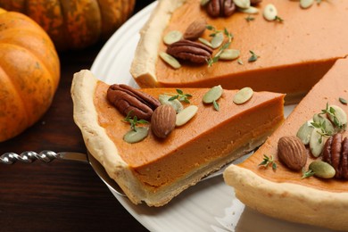 Photo of Taking piece of tasty homemade pumpkin pie at wooden table, closeup