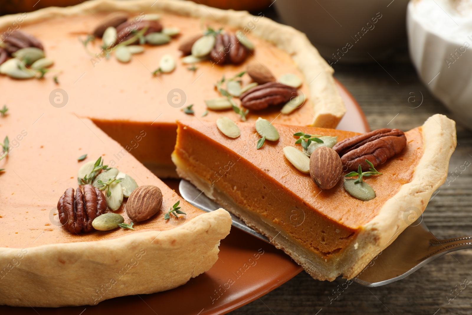 Photo of Taking piece of tasty homemade pumpkin pie at wooden table, closeup