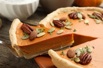 Photo of Taking piece of tasty homemade pumpkin pie at wooden table, closeup