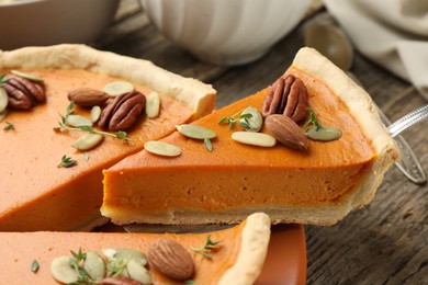 Photo of Taking piece of tasty homemade pumpkin pie at wooden table, closeup