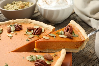 Photo of Taking piece of tasty homemade pumpkin pie at wooden table, closeup