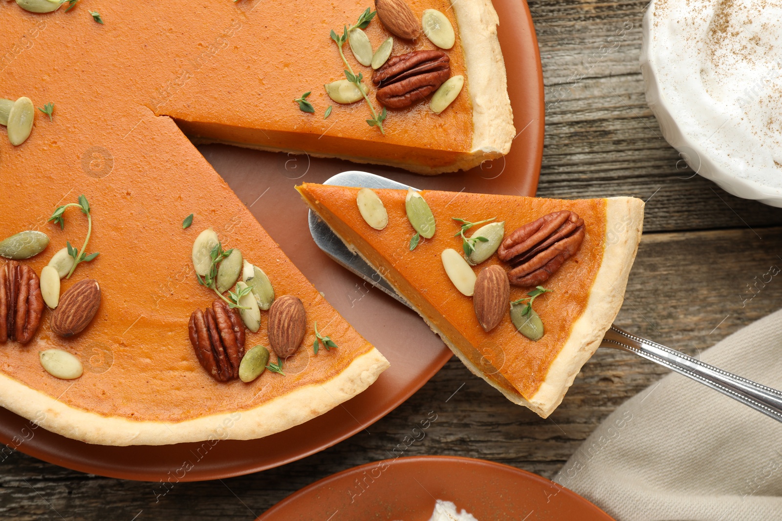 Photo of Taking piece of tasty homemade pumpkin pie at wooden table, top view