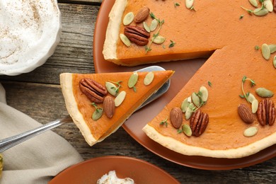 Photo of Taking piece of tasty homemade pumpkin pie at wooden table, top view