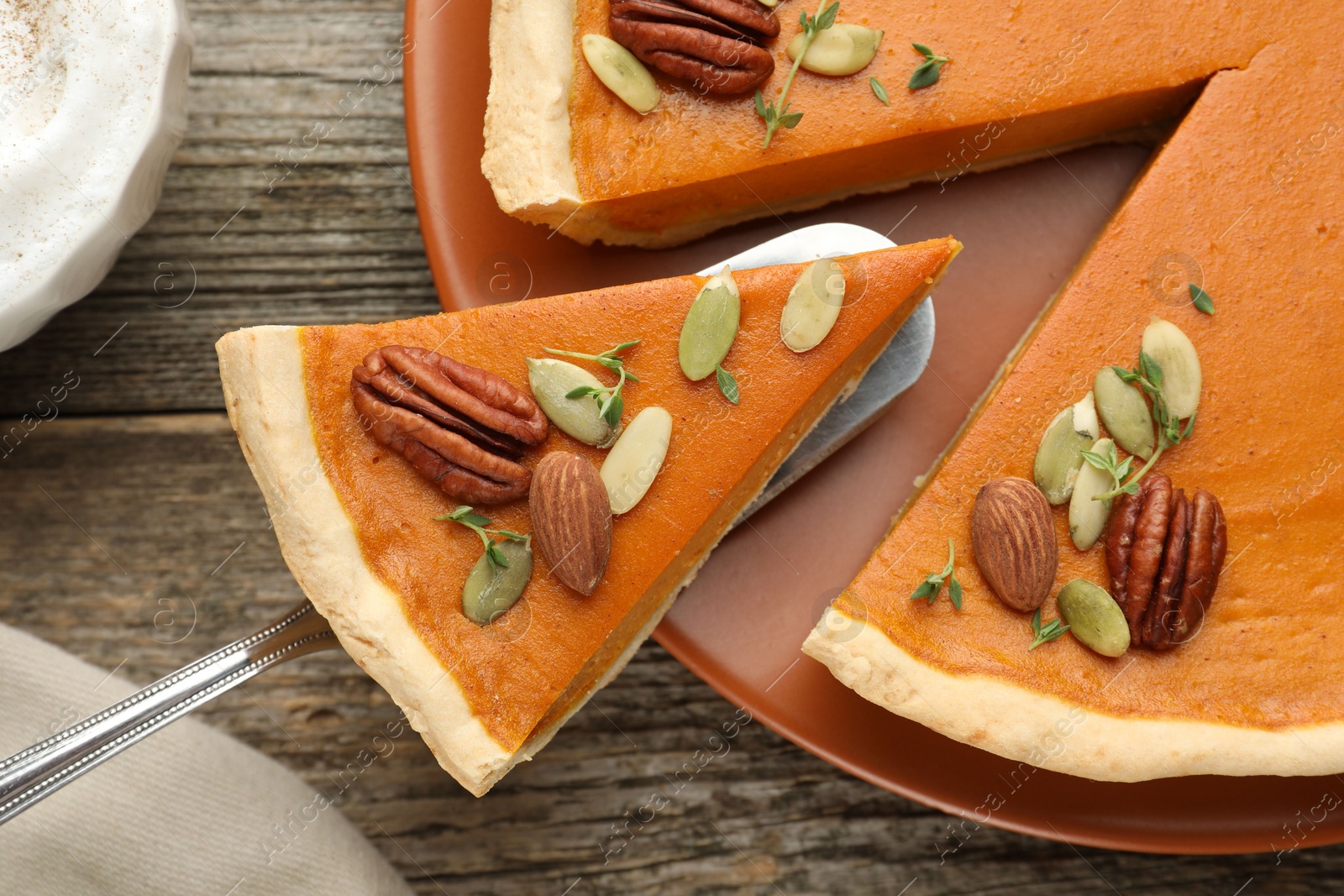 Photo of Taking piece of tasty homemade pumpkin pie at wooden table, top view