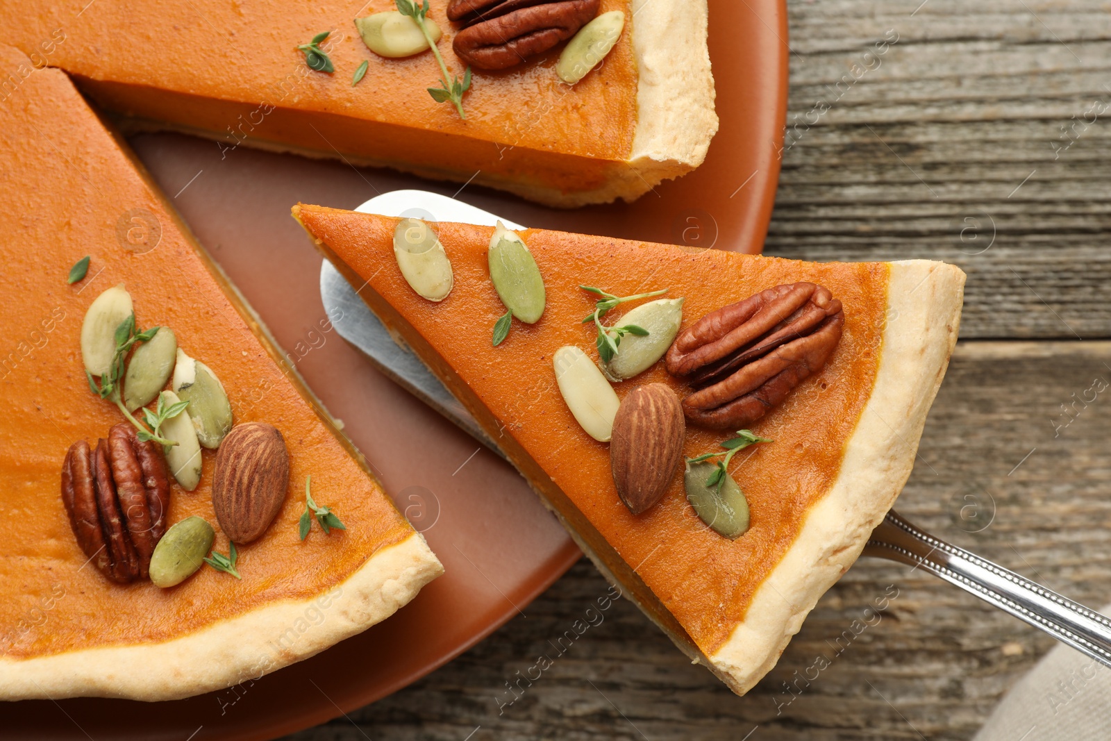 Photo of Taking piece of tasty homemade pumpkin pie at wooden table, top view