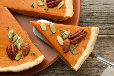 Taking piece of tasty homemade pumpkin pie at wooden table, top view