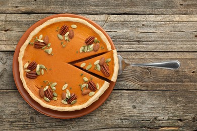 Tasty homemade pumpkin pie and server on wooden table, top view