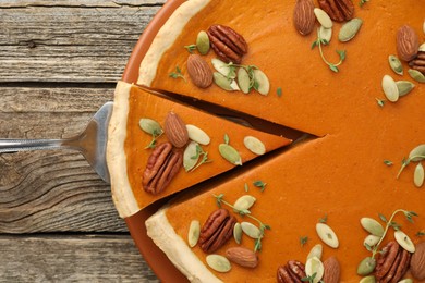 Photo of Taking piece of tasty homemade pumpkin pie at wooden table, top view