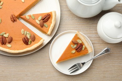 Photo of Tasty homemade pumpkin pie served on wooden table, top view