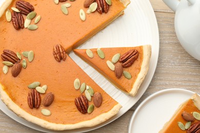 Photo of Tasty homemade pumpkin pie served on wooden table, top view