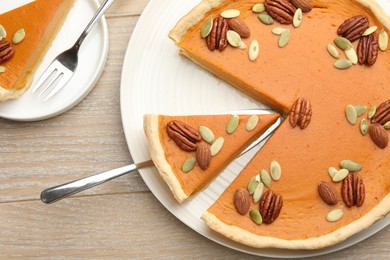 Photo of Tasty homemade pumpkin pie served on wooden table, top view