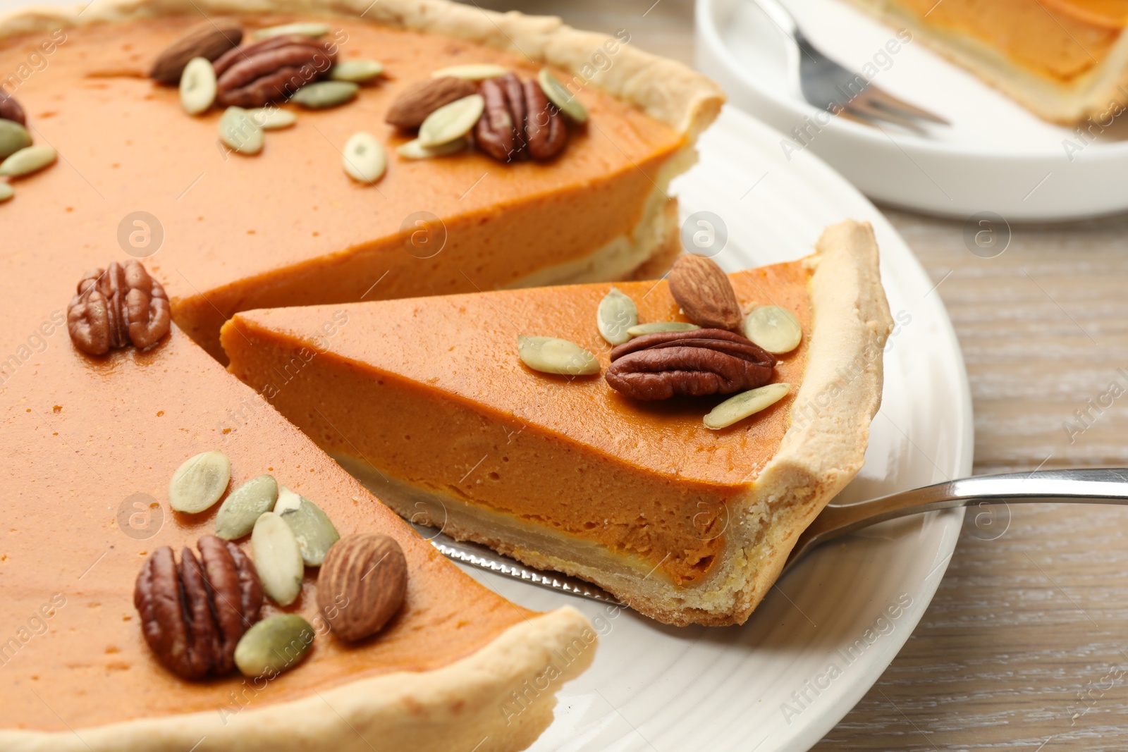 Photo of Taking piece of tasty homemade pumpkin pie at wooden table, closeup