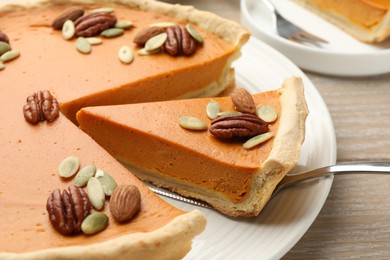 Photo of Taking piece of tasty homemade pumpkin pie at wooden table, closeup