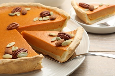 Photo of Taking piece of tasty homemade pumpkin pie at wooden table, closeup