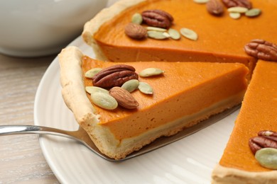 Photo of Taking piece of tasty homemade pumpkin pie at table, closeup