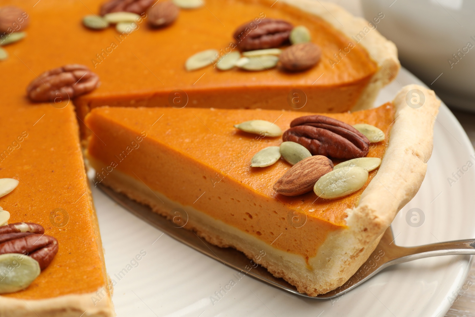 Photo of Taking piece of tasty homemade pumpkin pie at table, closeup