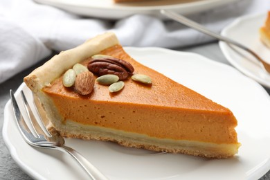 Photo of Piece of tasty homemade pumpkin pie with seeds and nuts on table, closeup