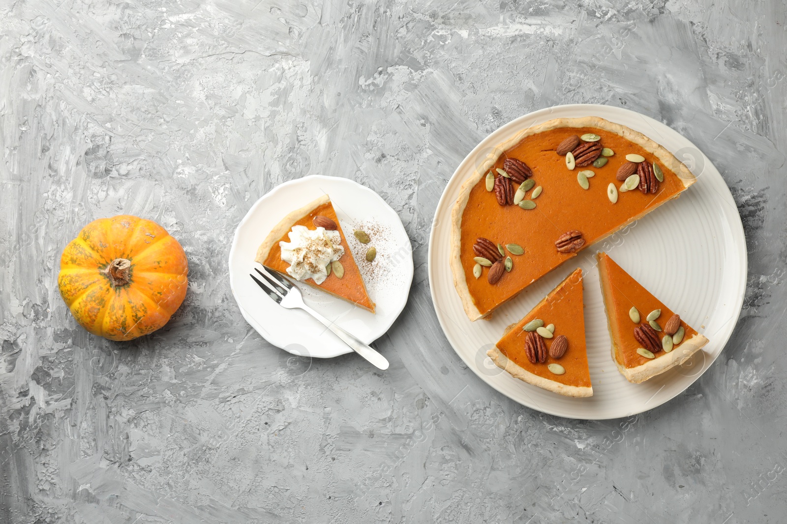 Photo of Pieces of tasty homemade pumpkin pie served on grey table, top view