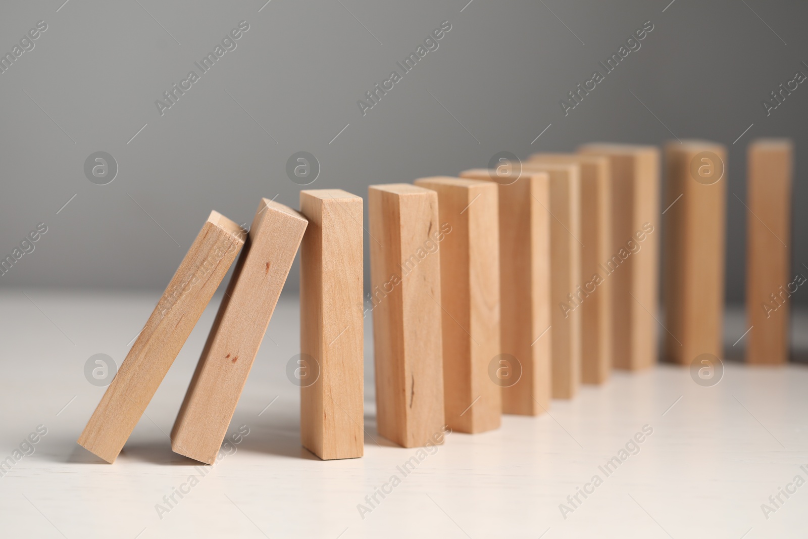 Photo of Domino effect. Wooden blocks falling on white table, closeup